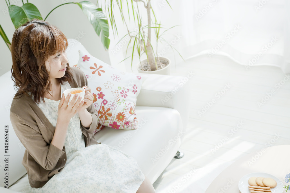 Young woman sitting on a sofa and drinking tea Young woman sitting on a sofa and drinking tea