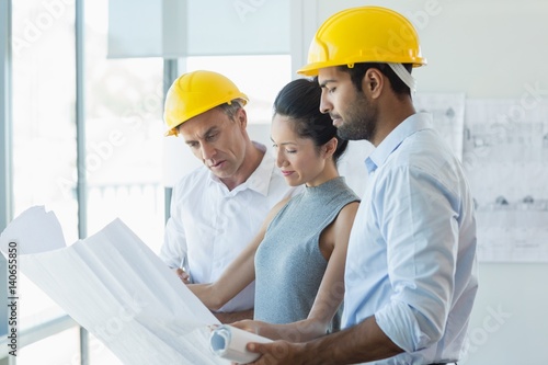 Three architects discussing over blueprint