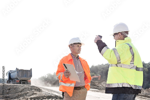Supervisors discussing at construction site against clear sky