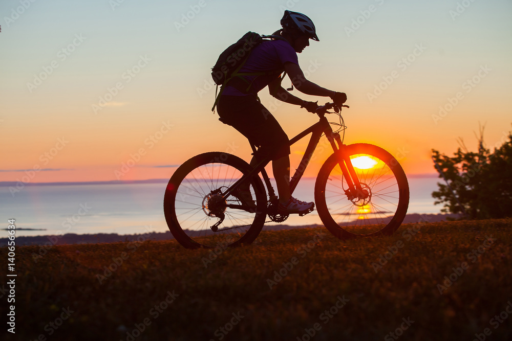 Obraz premium Woman mountain biking on single track trail at Sunset