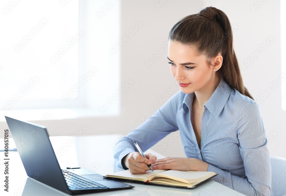 Beautiful young business woman writing in notebook Beautiful young business woman writing in notebook