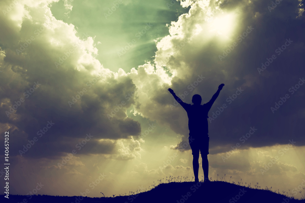Silhouette of man with hands raised and sky with sunlight Silhouette of man with hands raised and sky with sunlight
