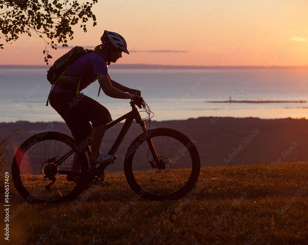 Obraz premium Woman mountain biking on single track trail at Sunset