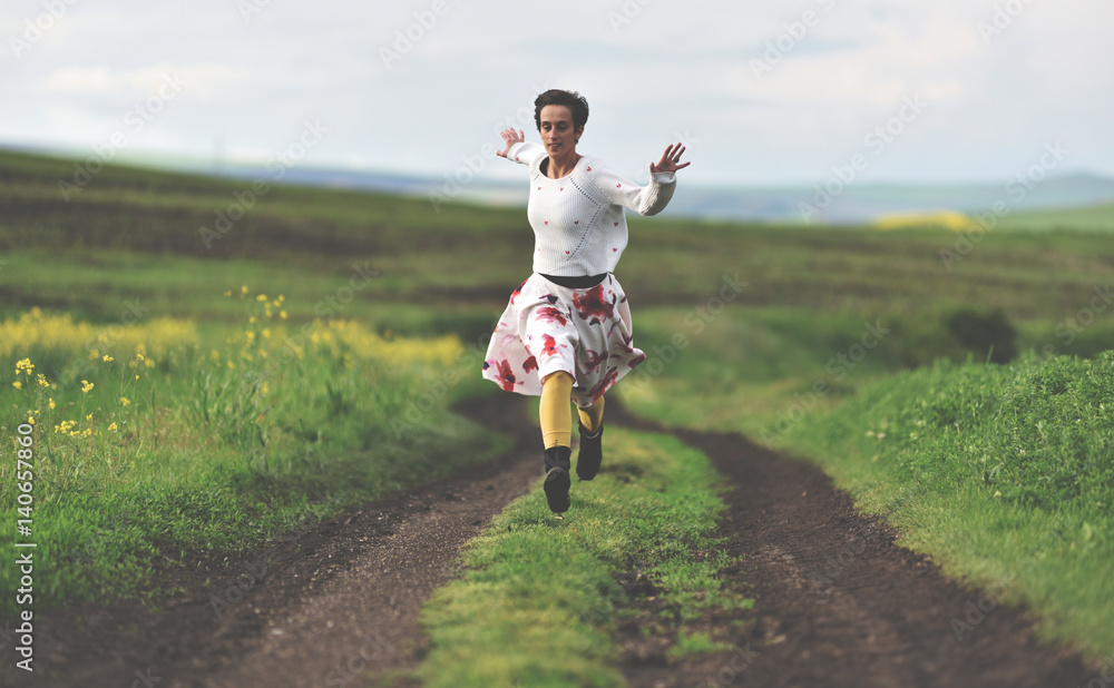 Freedom concept. Cheerful girl running on a countryside road Freedom concept. Cheerful girl running on a countryside road
