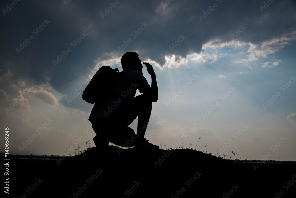Silhouette of man sitting and sky with sunlight
