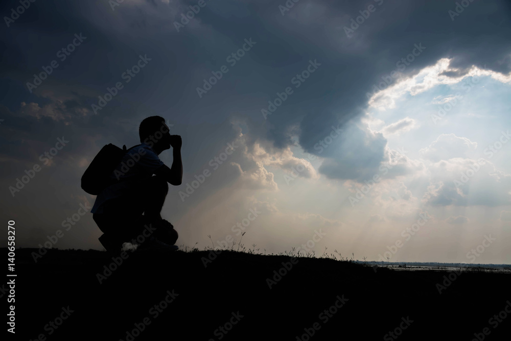 Silhouette of man sitting and sky with sunlight