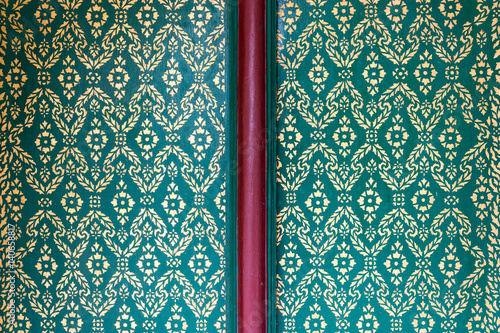 gold pianting flower pattern on green color background, traditional Thai style painted, temple door photo