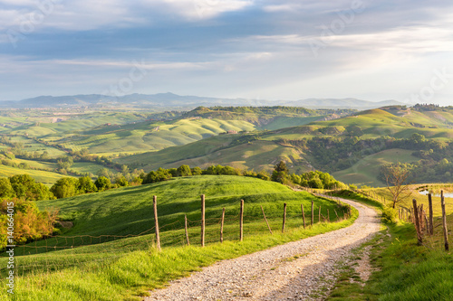 Rural view of the valley with a rolling landscape and a dirt road in Tuscany, Italy photo
