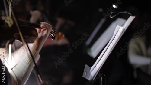 Close-up of musician playing violin on the dark.