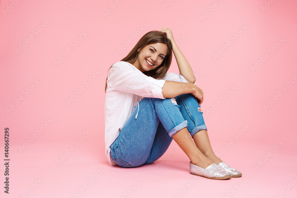 Young smiling girl sitting on floor hugging knees looking straight Young smiling girl sitting on floor hugging knees looking straight