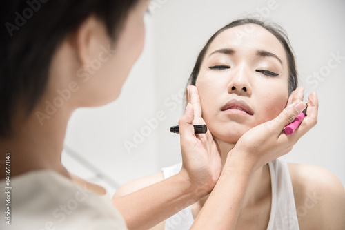 Make up artist applying make up to a clean face fashion model or bride