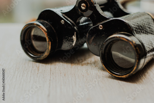 Vintage binoculars on a white wooden background