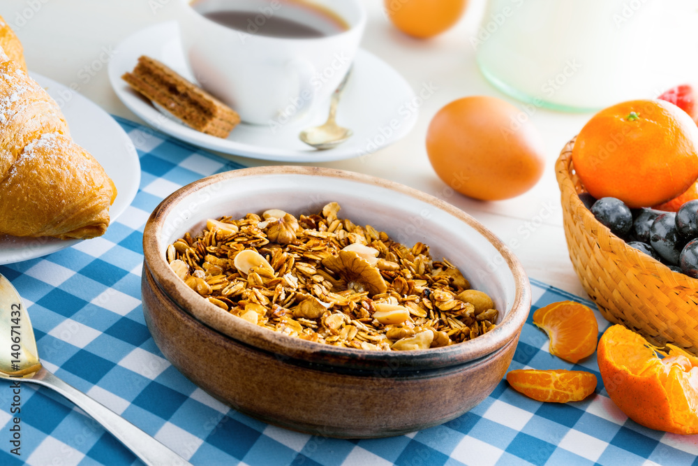 Delicious healthy breakfast with oatmeal granola, fruits, eggs, coffee and croissant on a white wooden table. Traditional healthy food. Close-up. Delicious healthy breakfast with oatmeal granola, fruits, eggs, coffee and croissant on a white wooden table. Traditional healthy food. Close-up.