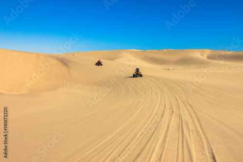 Quad driving people - two happy bikers in sand desert.