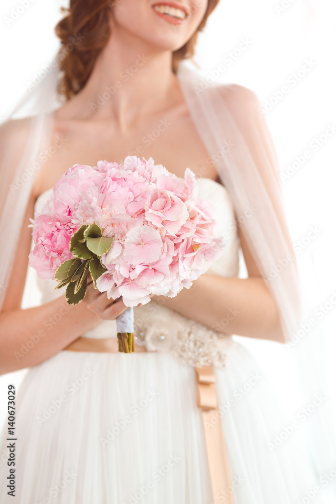 Obraz premium Bridal bouquet of pink wedding flowers in hands of the bride