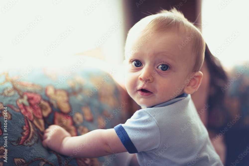 Baby Close Up Standing. baby holding onto side of couch standing up looking at camera Baby Close Up Standing. baby holding onto side of couch standing up looking at camera