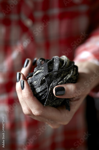 Hand holding black pasta.