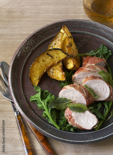 Pork tenderloin with acorn squash and greens on a plate.