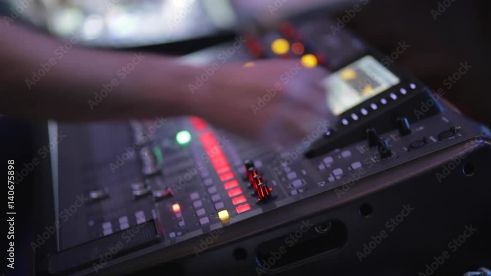 The man controls the mixer during a concert in the dark. The man controls the mixer during a concert in the dark.