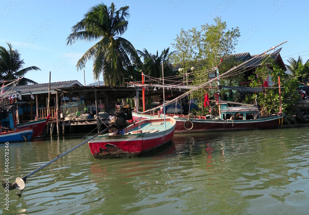 A few traditional fishing boats on front of a village, Thailand
