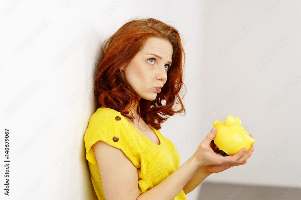 nachdenkliche frau hält ein sparschwein in händen