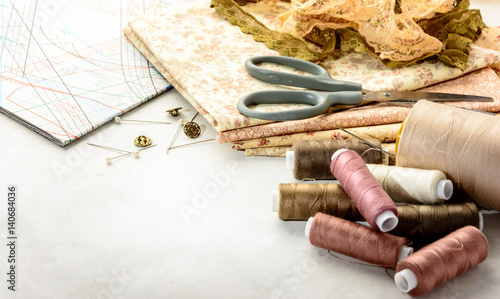 Accessories for sewing and cutting lie on a white table.  Space for an object.