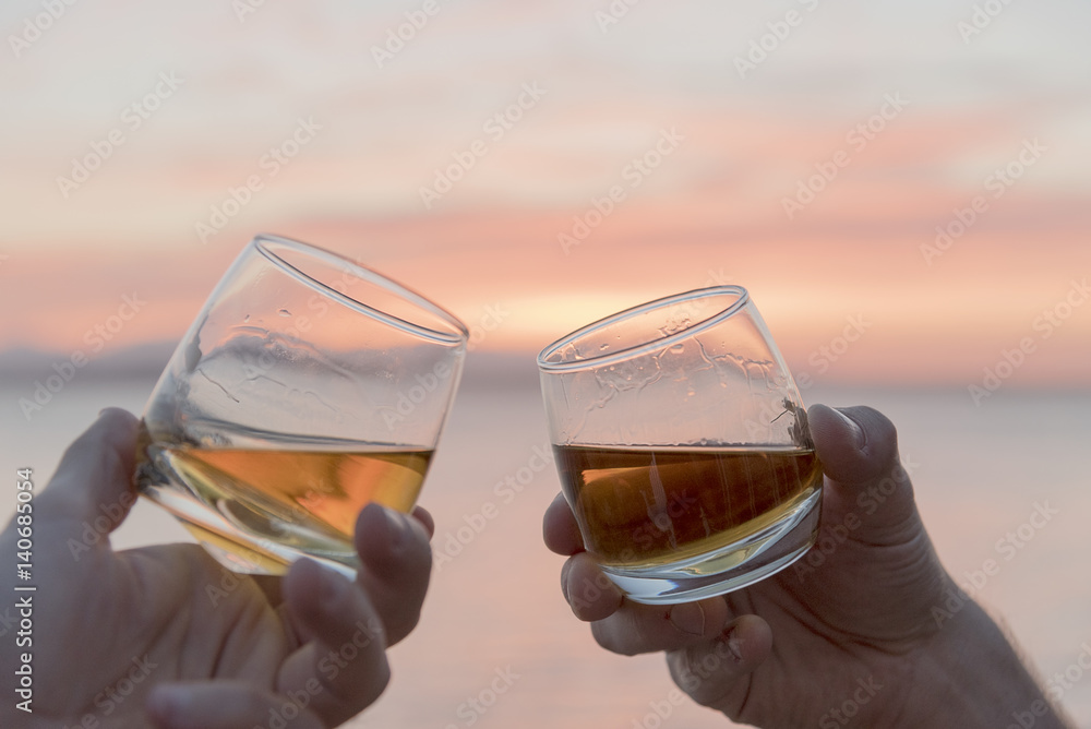 Close up two mens hands toasting whiskey drams