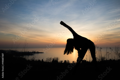 silhouette of woman stretching in front of sunrise