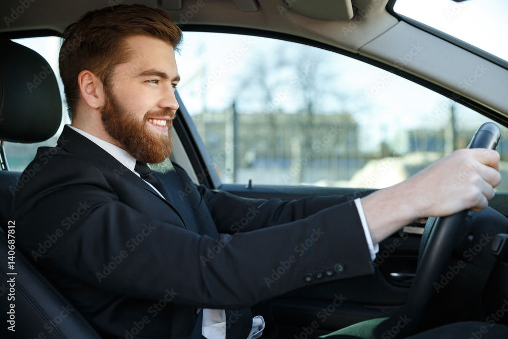 Side view of smiling business man sitting at the wheel Side view of smiling business man sitting at the wheel