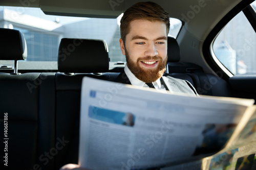 Pleased business man reading newspaper