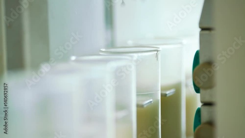 Milk analysis. Analysis of milk sample on laboratory equipment. Modern equipment. Scientist put glass with milk in laboratory equipment for research. Food quality test photo