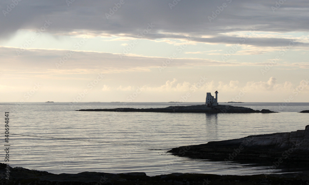 Silhouette einer Insel mit Leuchtturm Hestskjaer am Altanterhavsveien bei Kristiansund  / Norwegen im abendlichen Gegenlicht