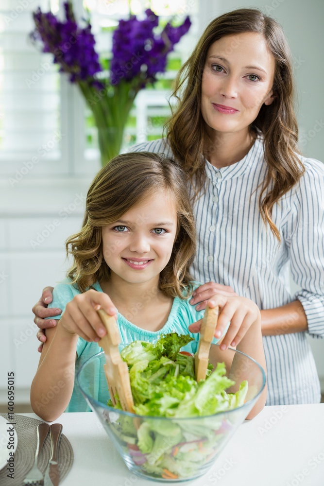 smiling mother and daughter mixing bowl of salad smiling mother and daughter mixing bowl of salad