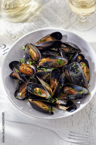Bowl of mussels in white wine sauce garnished with parsley