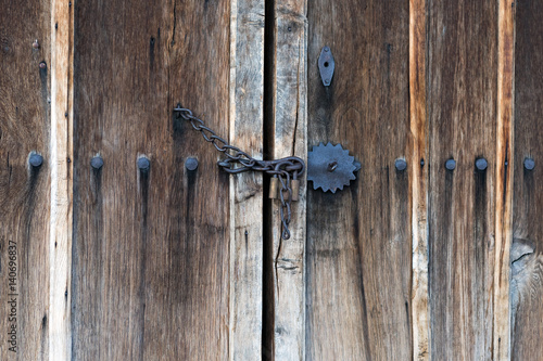 Chain locked wooden door with big iron nails and metal ornaments
