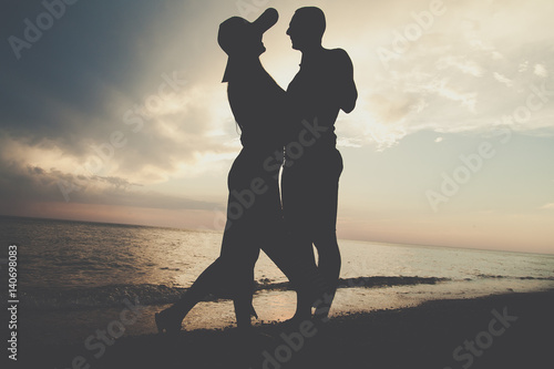 Loving couple on the beach. people stand at sunset in the shade.