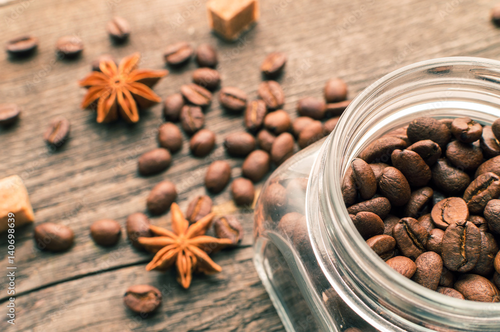 Coffee beans into glass jar table with sugar and anise Coffee beans into glass jar table with sugar and anise