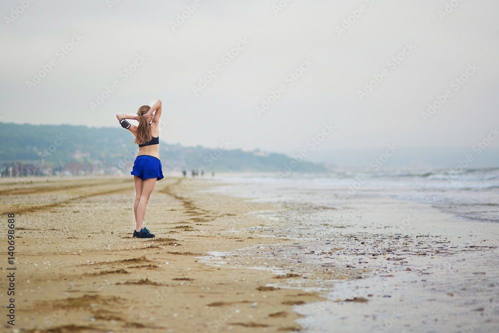 Woman on beach doing stretching exercise after a workout