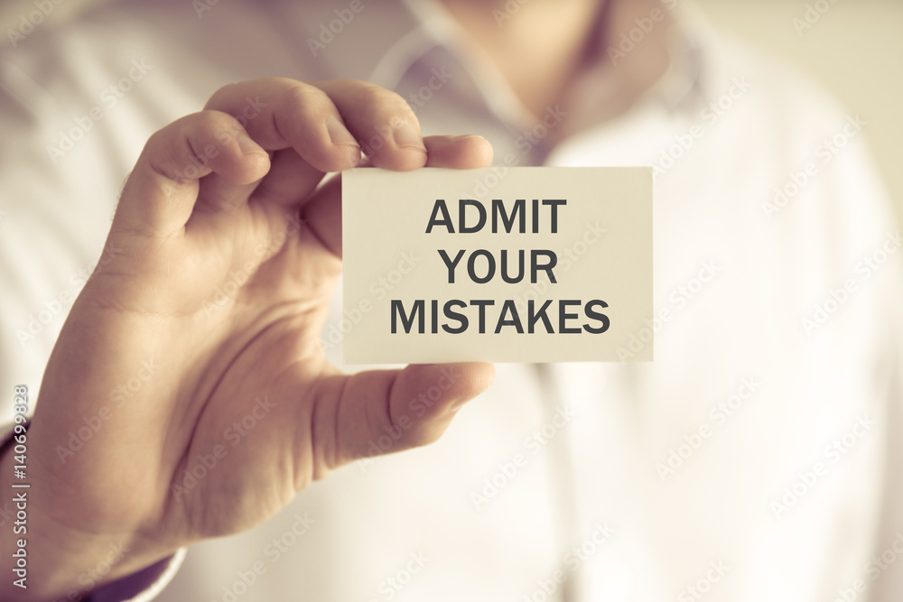 Businessman holding ADMIT YOUR MISTAKES message card Businessman holding ADMIT YOUR MISTAKES message card