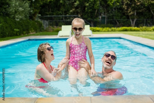 Happy parents and daughter having fun in pool