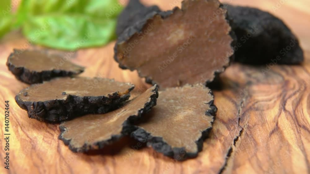 Thin slices and tubers of black truffle lying on a wooden board Thin slices and tubers of black truffle lying on a wooden board
