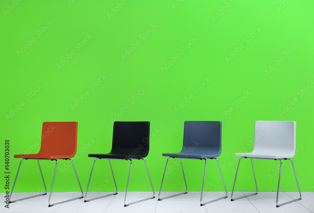 Fototapeta premium Modern chairs in a row on green wall background