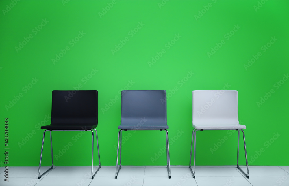 Modern chairs in a row on green wall background Modern chairs in a row on green wall background