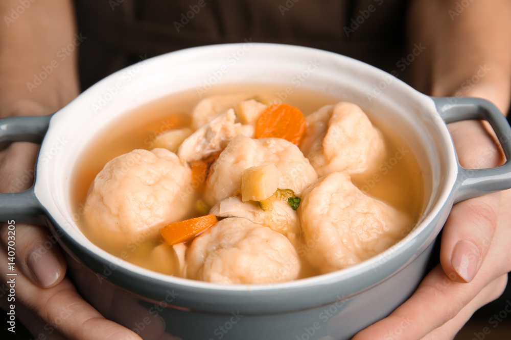 Female hands holding ceramic pan with delicious chicken and dumplings Female hands holding ceramic pan with delicious chicken and dumplings