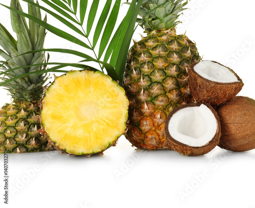 Fresh pineapples and coconuts on white background, closeup