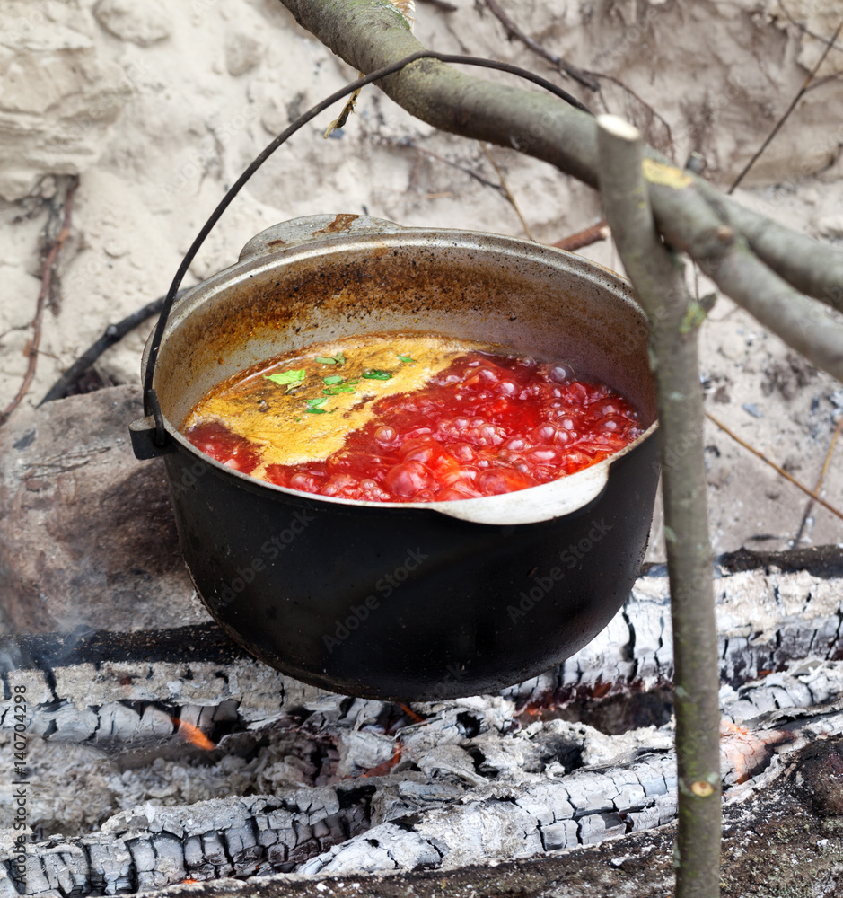 Soup cooking in sooty cauldron on campfire Soup cooking in sooty cauldron on campfire