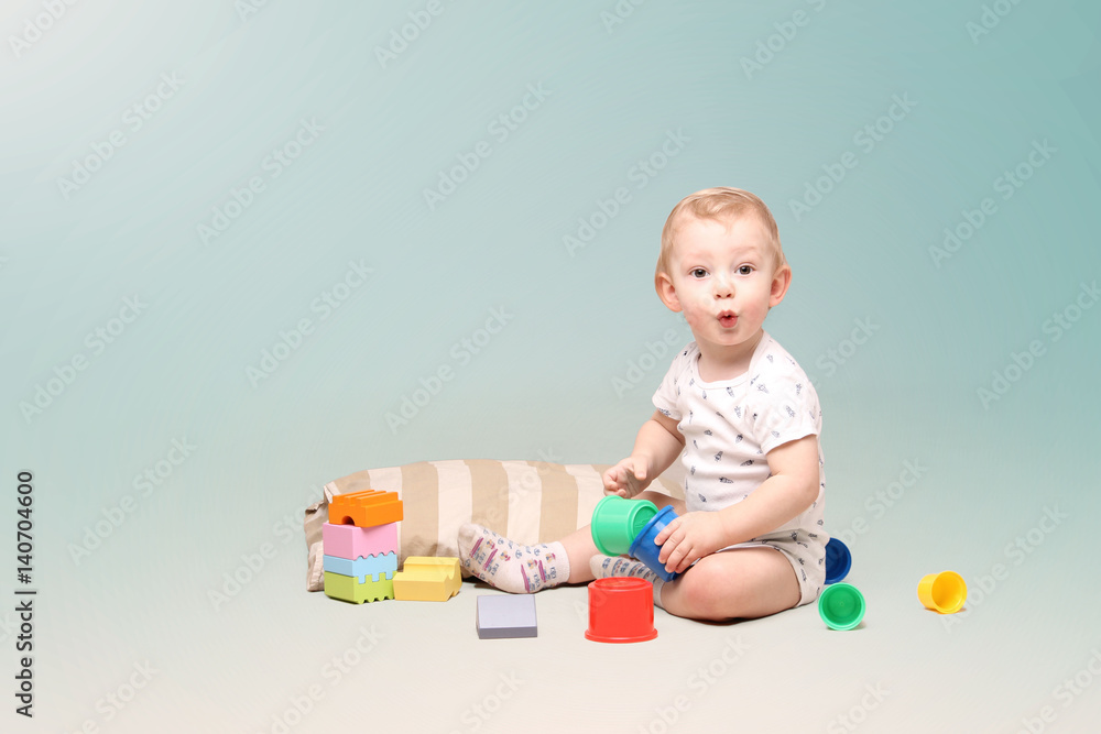 Surprised little baby boy sitting on the floor and playing with some toys. Surprised little baby boy sitting on the floor and playing with some toys.