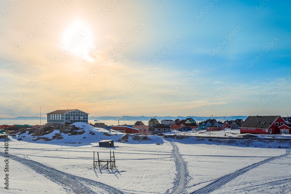 Sun, sky and snow covered Ilulissat city with fjord in background, Greenland