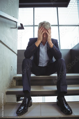 Depressed businessman sitting with hand on head