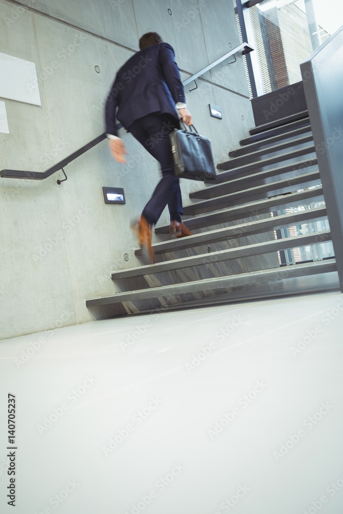 Businessman climbing stairs at office Businessman climbing stairs at office